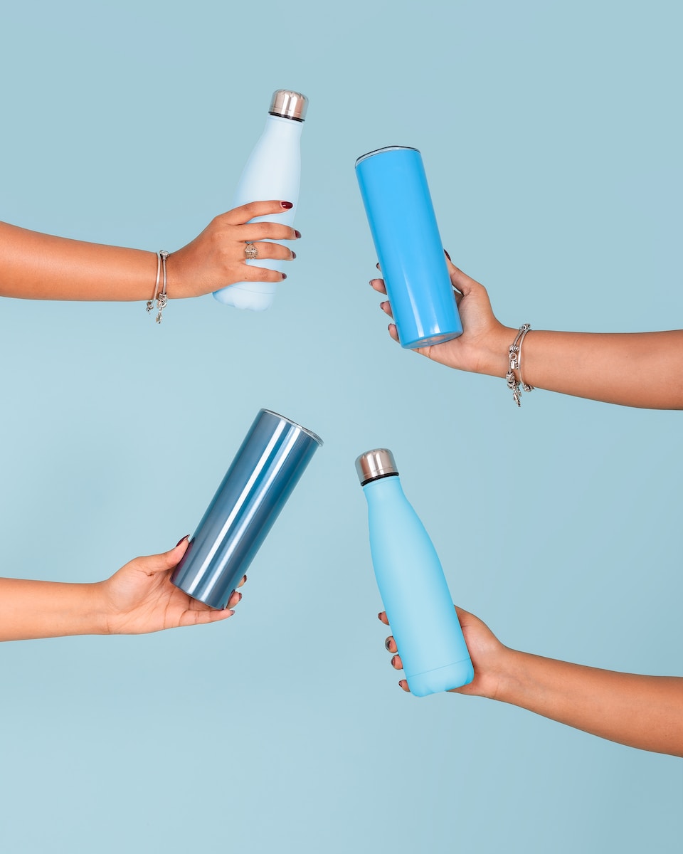 a group of people holding different colored water bottles